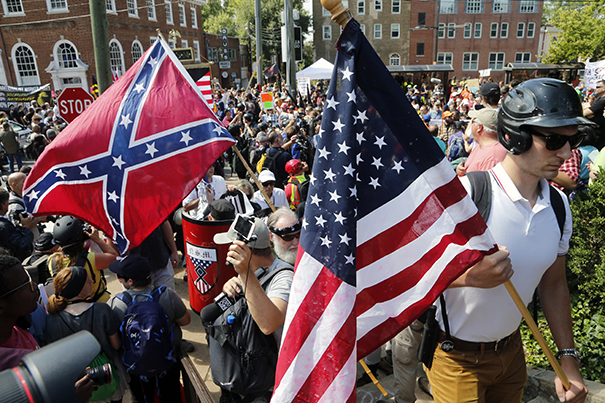 White nationalist demonstrators walk into Lee park surrounded by counter demonstrators in Charlottesville, Va., Saturday, Aug. 12, 2017. Gov. Terry McAuliffe declared a state of emergency and police dressed in riot gear ordered people to disperse after chaotic violent clashes between white nationalists and counter protestors. (AP Photo/Steve Helber)